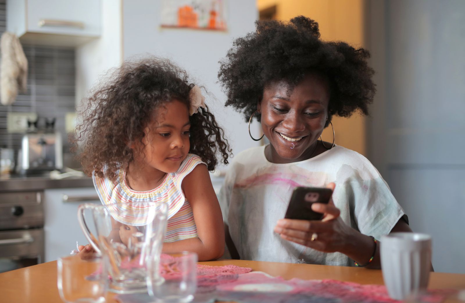 Mulher segurando celular ao lado de sua filha