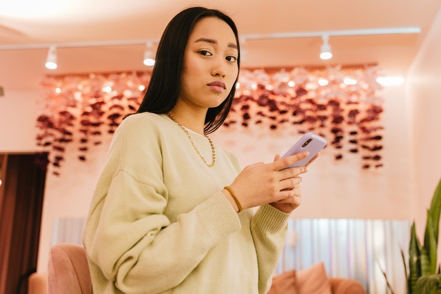 Mulher asiática segurando celular.