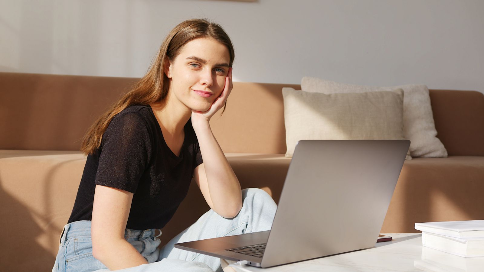 Mulher sorrindo olhando para o lado em frente ao seu computador 