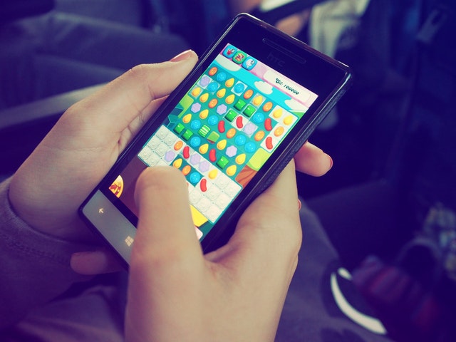 Par de mãos brancas segurando um celular ligado num jogo