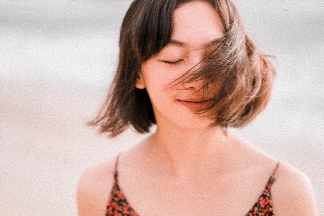 Mulher branca de cabelos curtos e castanhos com os olhos fechados.