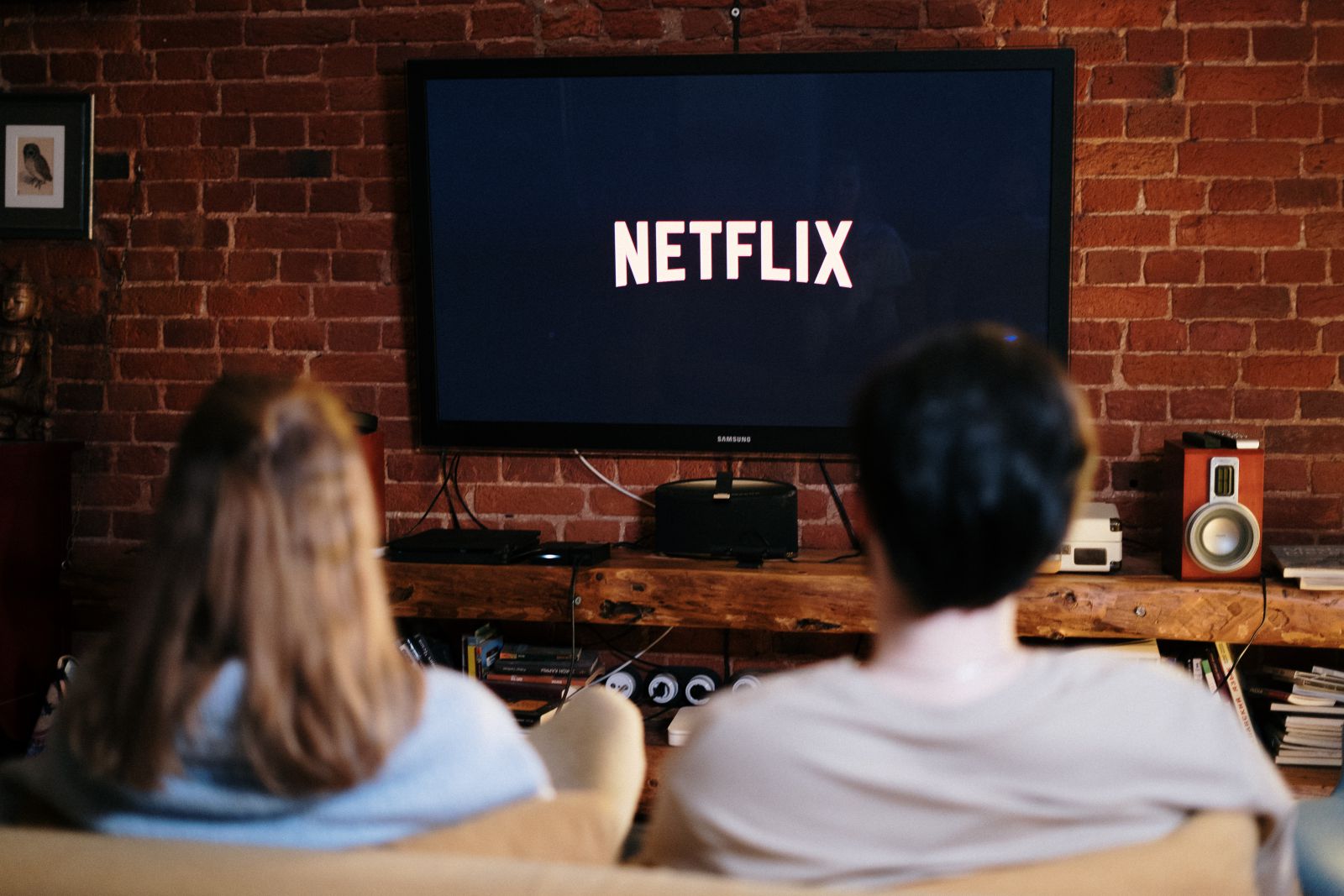 Homem e mulher sentados no sofá com a TV ligada