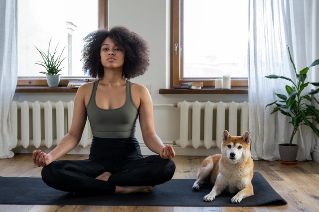 Mulher sentada no chão ao lado de seu cachorro, meditando
