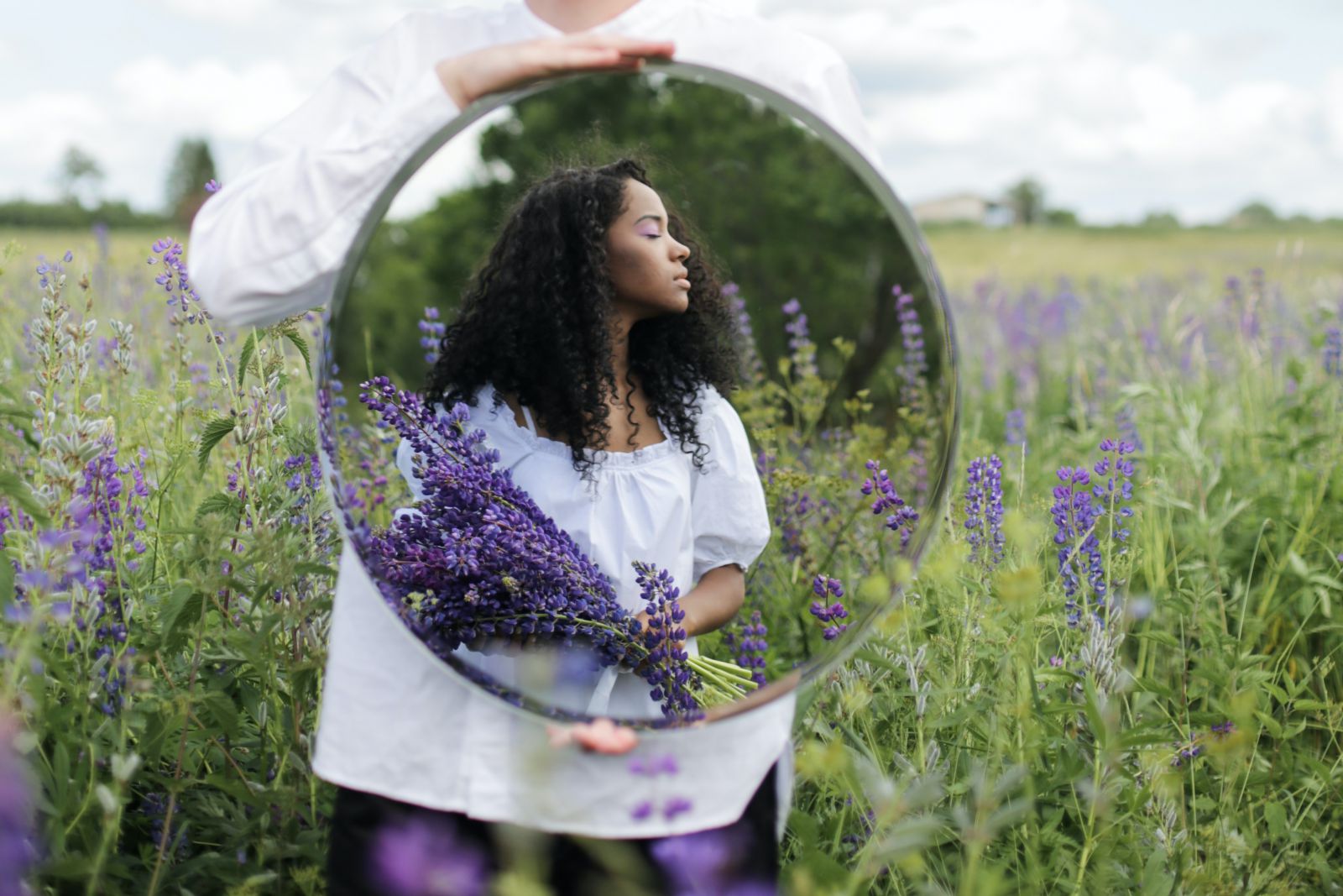 Mulher em um campo de flores segurando lavanda 