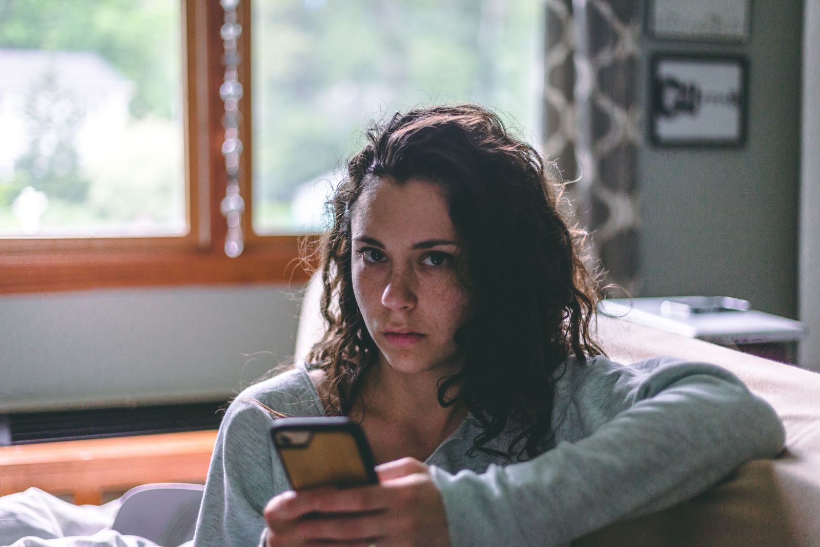 Mulher sentada no sofá segurando celular