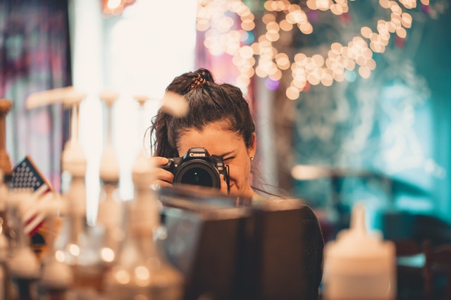 Mulher branca segurando câmera fotográfica.