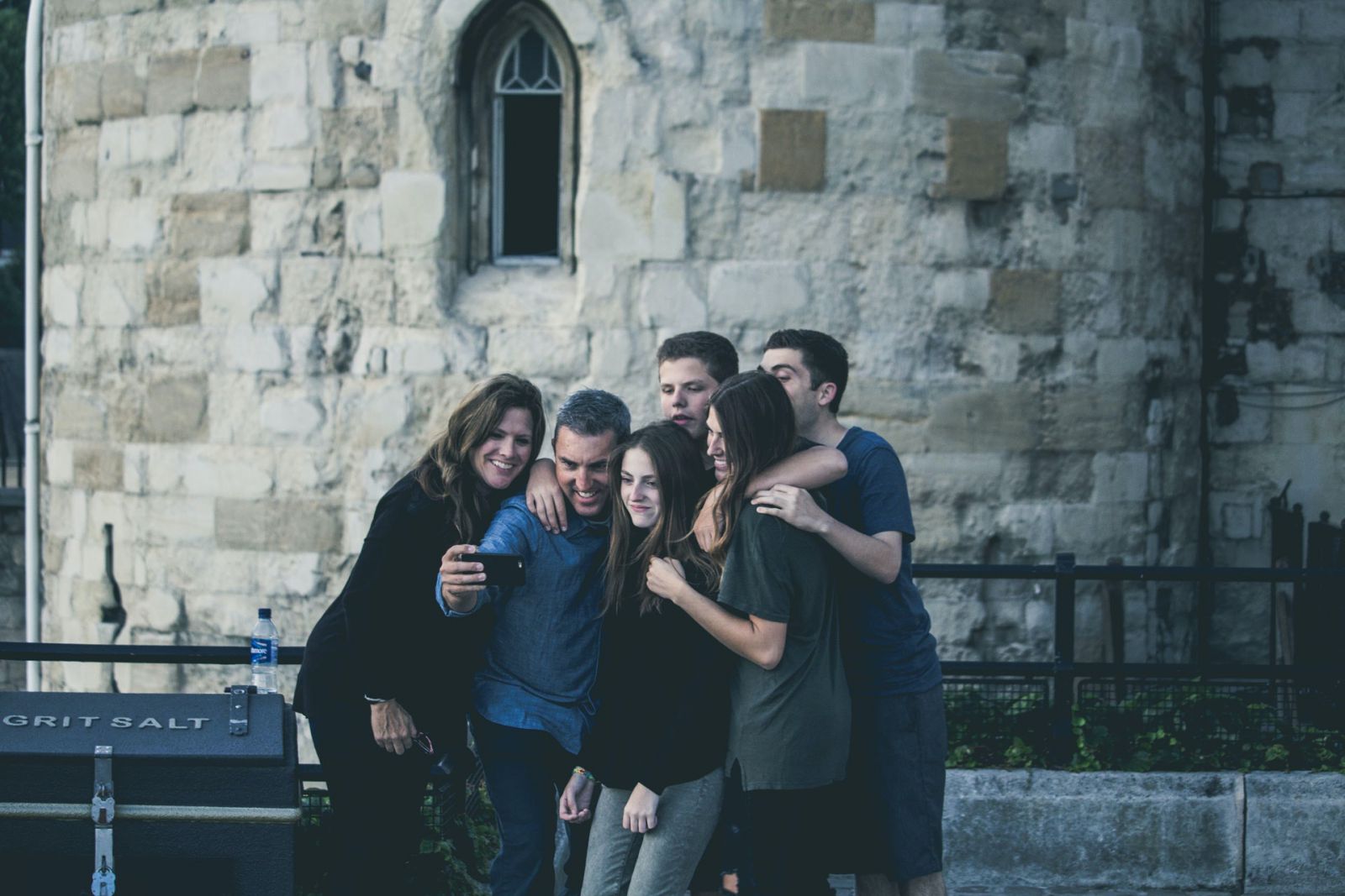 Família de mulheres e homens brancos abraçados tirando uma foto com o celular.