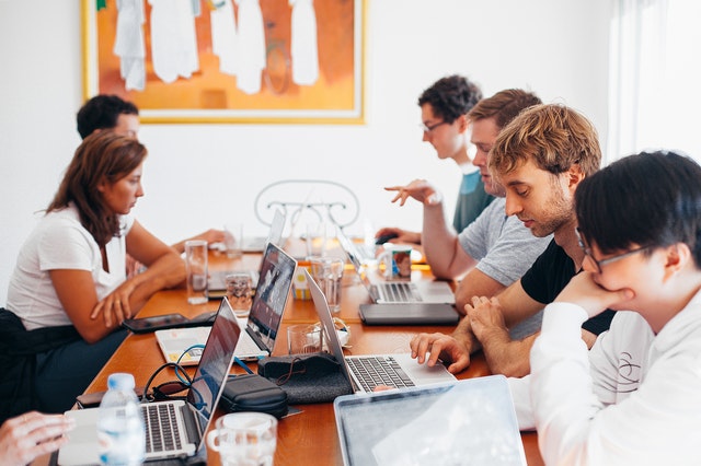 Pessoas numa mesa trabalhando com notebooks.
