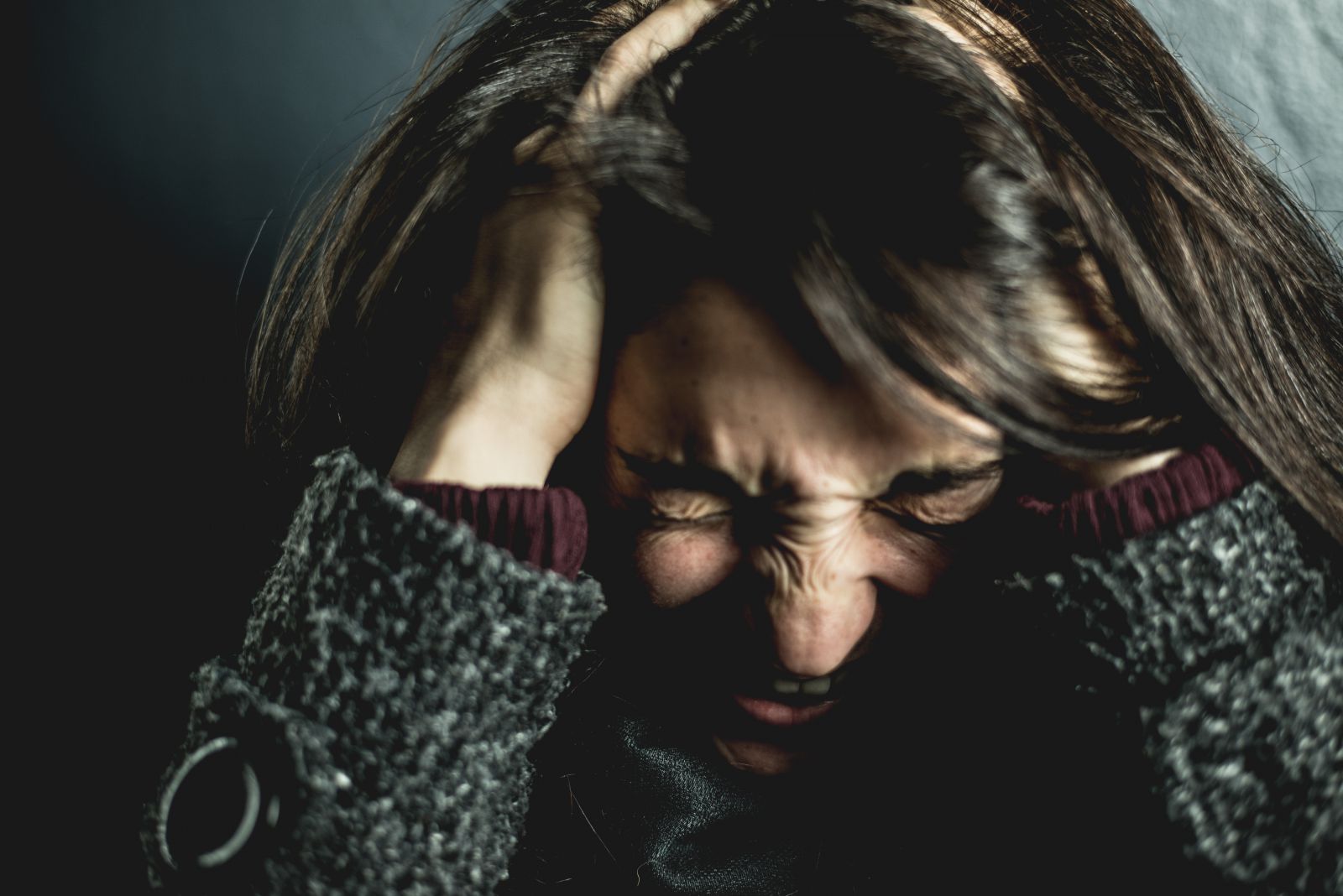 Mulher de olhos fechados com as mãos segurando sua cabeça