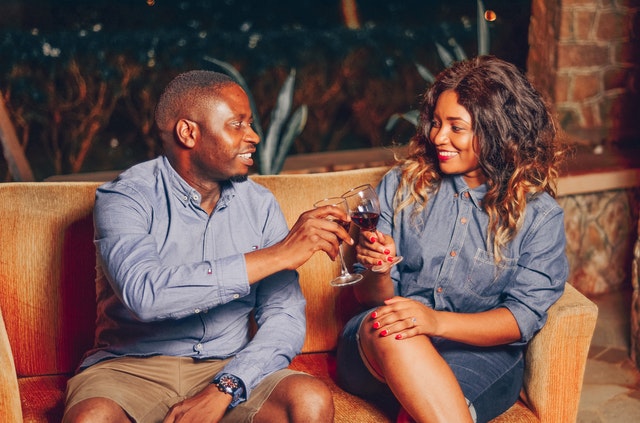 Homem e mulher negros brindando taças.
