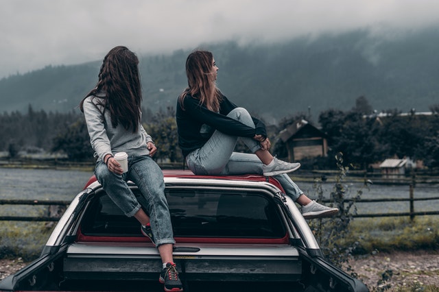 Duas mulheres sobre uma caminhonete, em frente a um rio