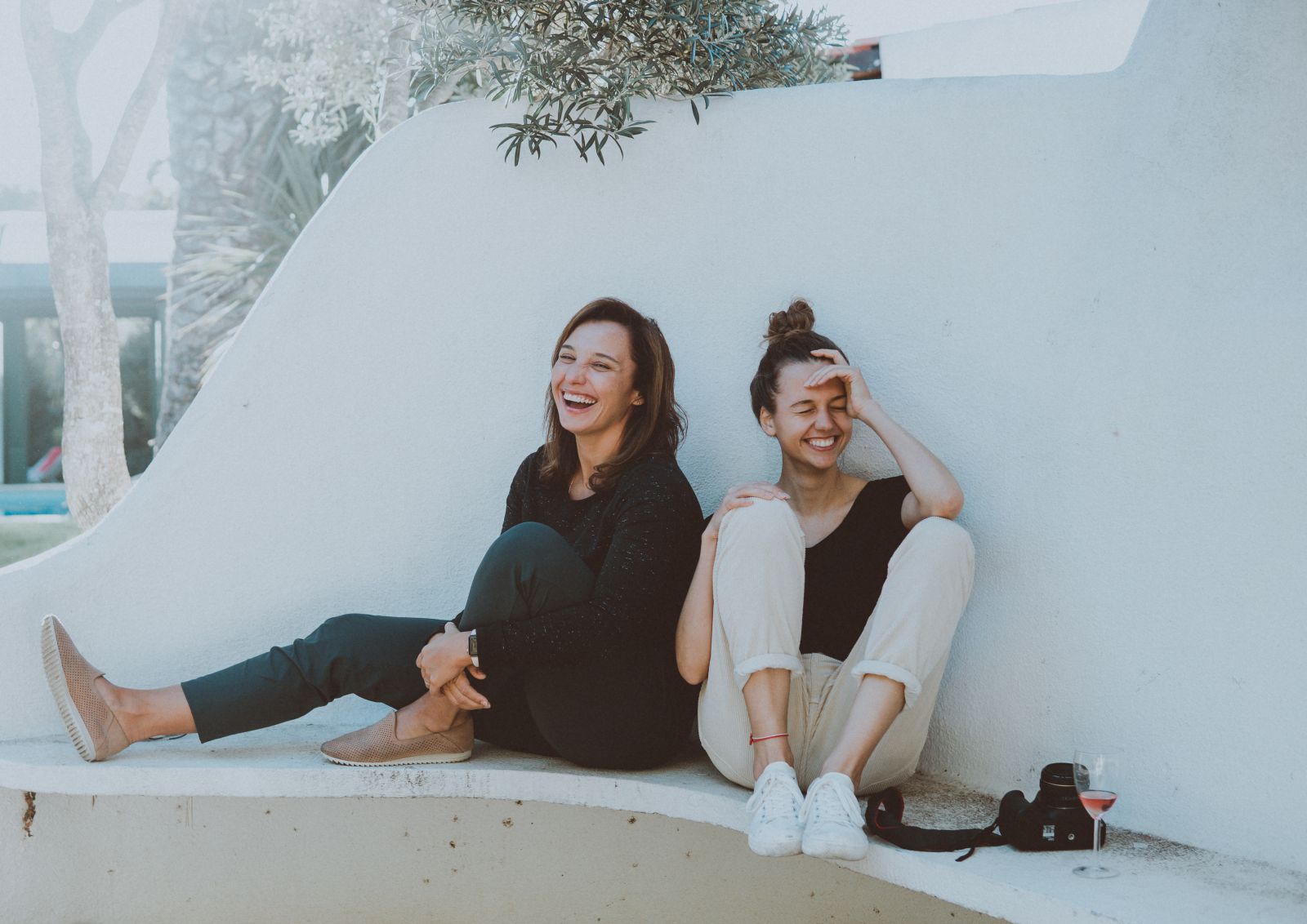 Duas amigas sentadas em um banco rindo