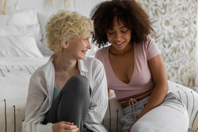 Duas mulheres se olhando sentadas em frente a cama