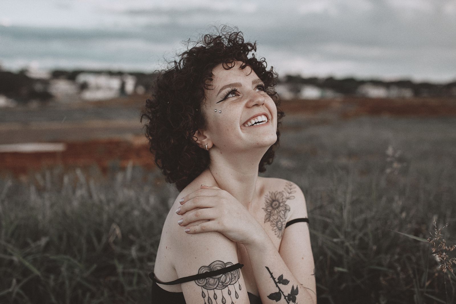 Mulher sentada em um gramado sorrindo e olhando para o céu