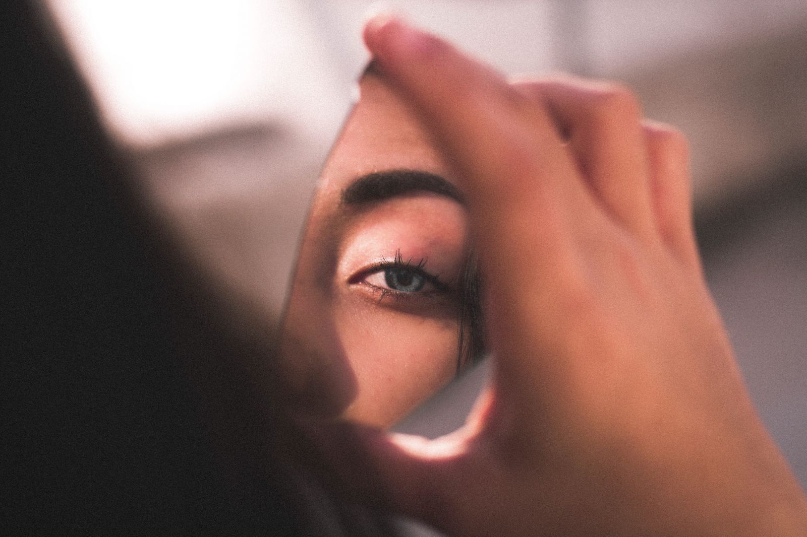 Mulher olhando para um pedaço de espelho