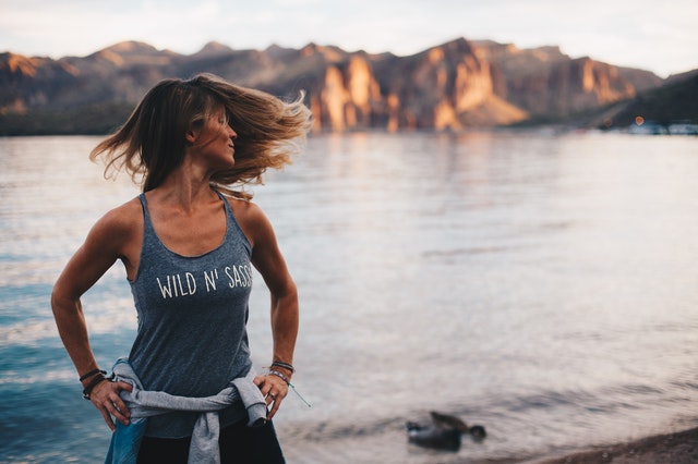 Mulher branca com roupas de ginástica e lago ao fundo.