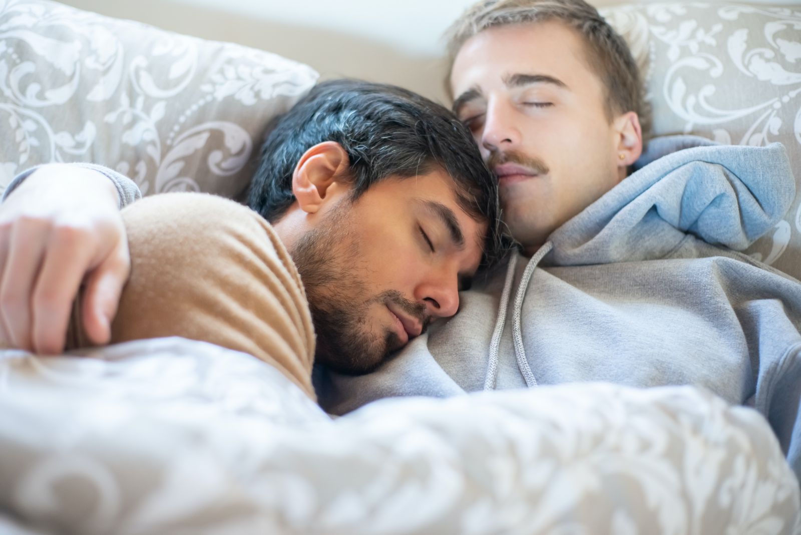 Casal de homens deitados na cama dormindo