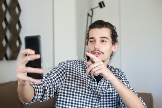 Homem branco fazendo brincadeiras com o celular.