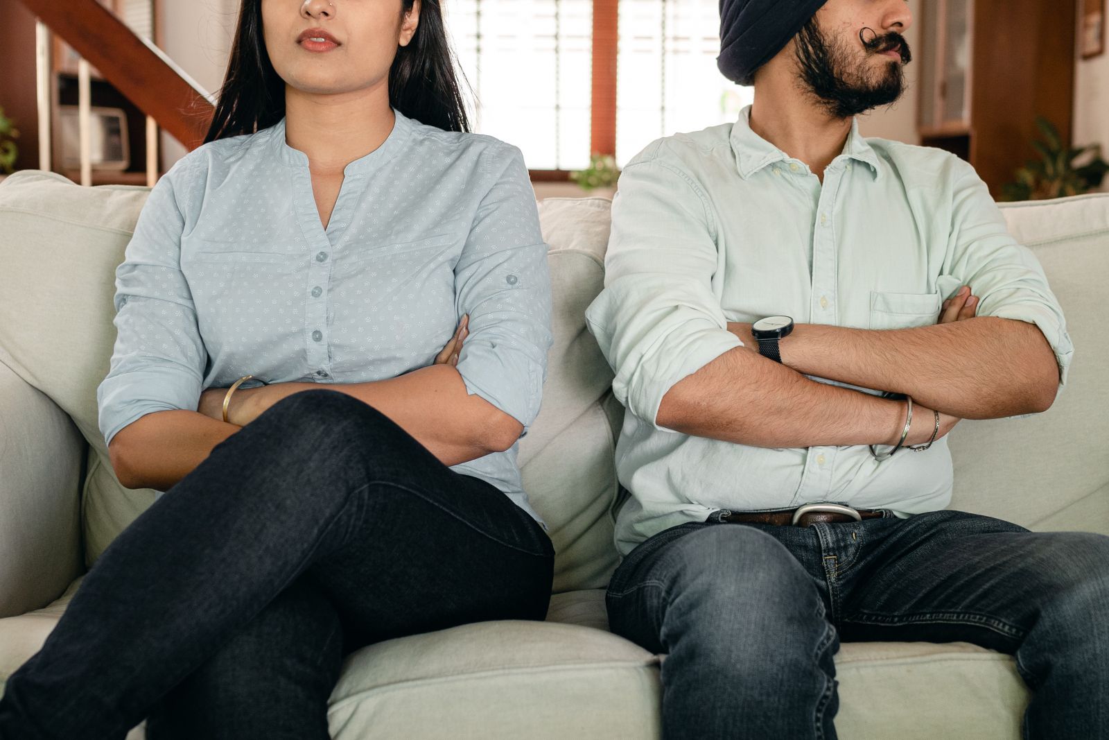 Homem e mulher sentados no sofá de braços cruzados