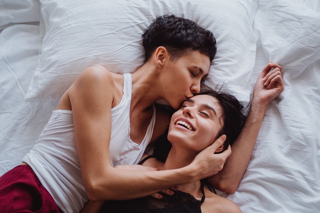 Mulheres brancas deitadas juntas numa cama.