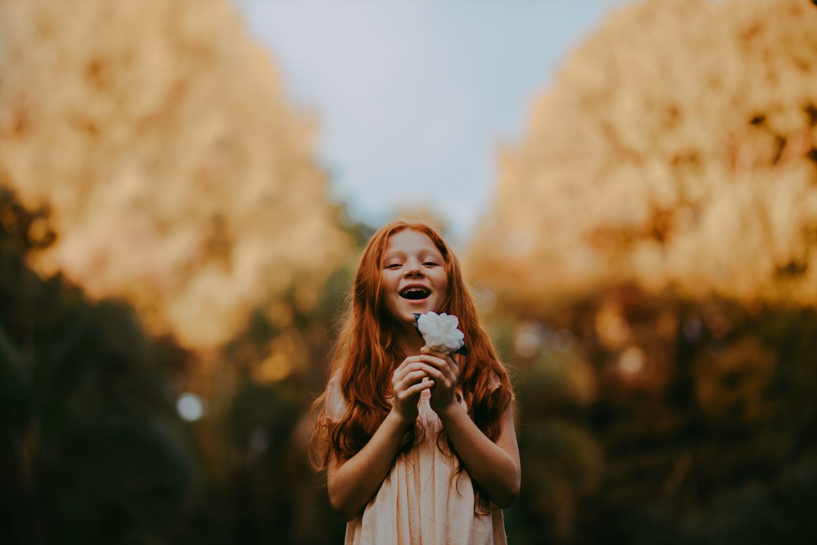 Criança sorrindo enquanto segura uma flor
