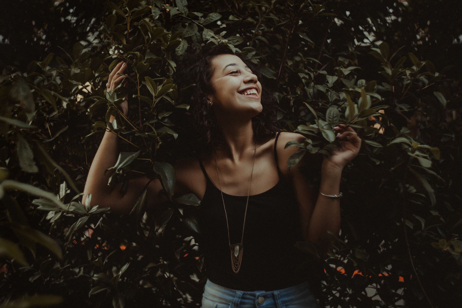 Mulher sorrindo olhando para o lado em seu jardim