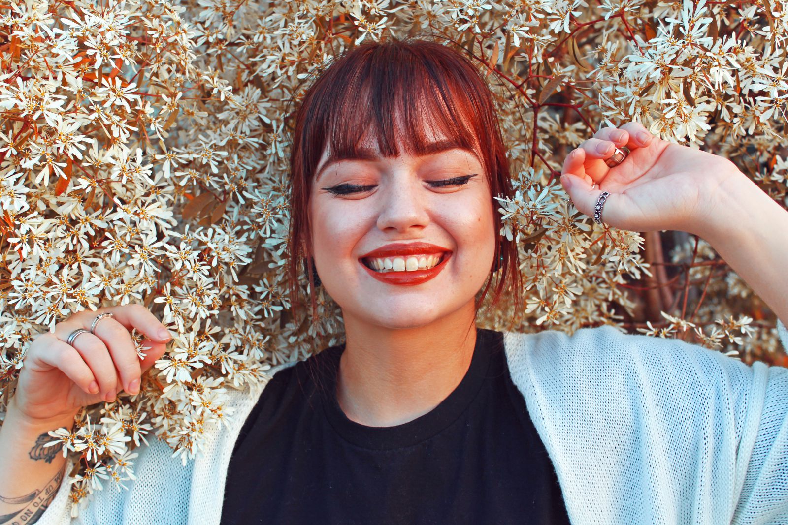 Mulher deitada em flores de olhos fechados e sorrindo