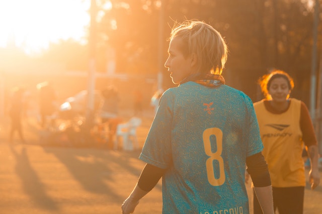 Jogadora loira e branca vestindo uma camiseta azul com o número 8