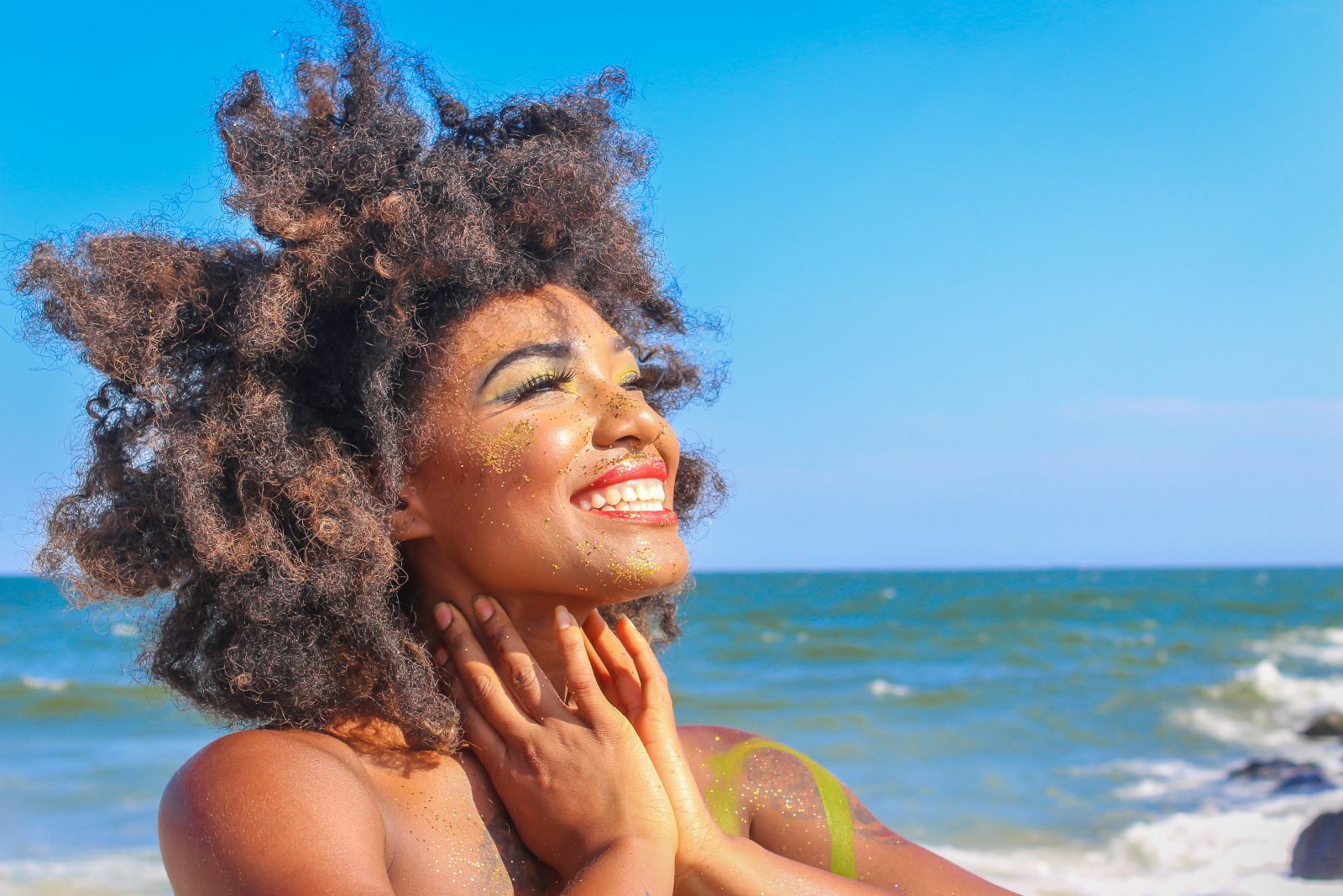 Mulher sorrindo na praia e olhando para cima