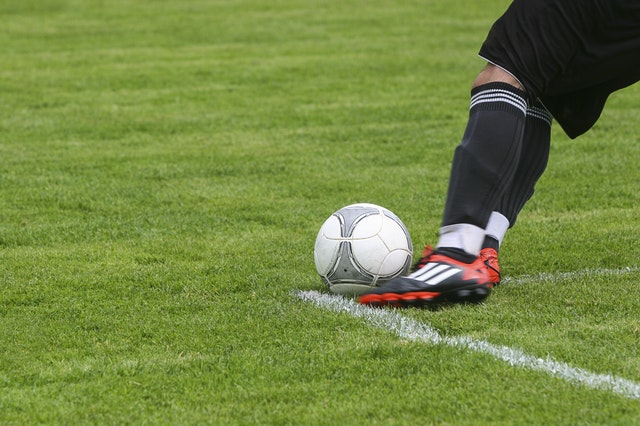 Par de pernas masculinas brancas jogando futebol num campo