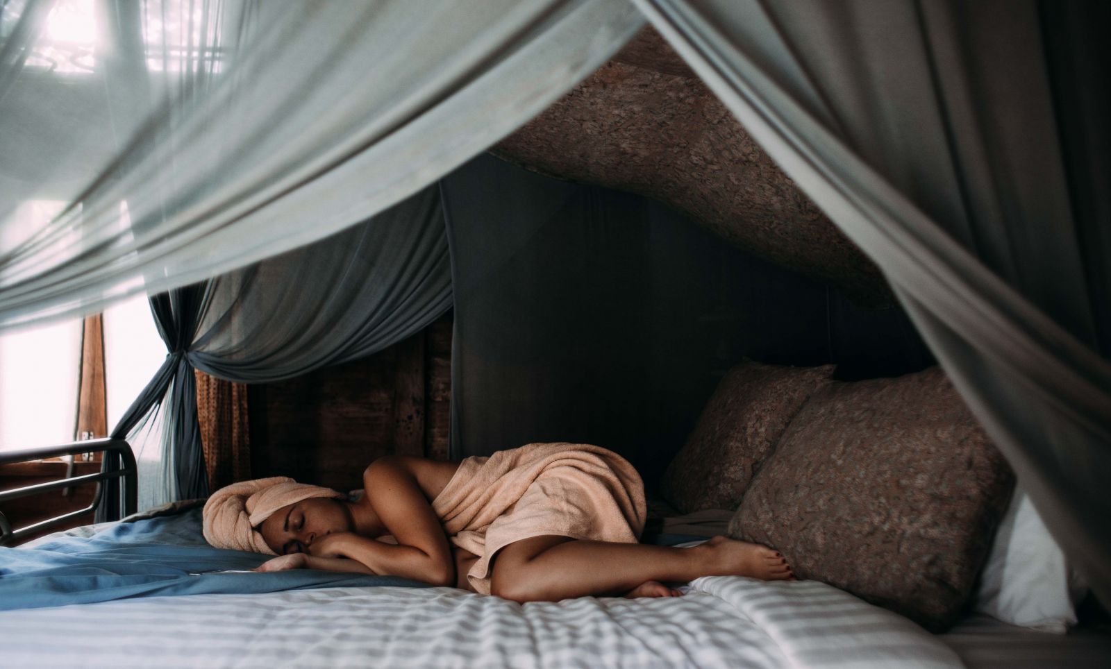Mulher deitada na cama com toalha de banho