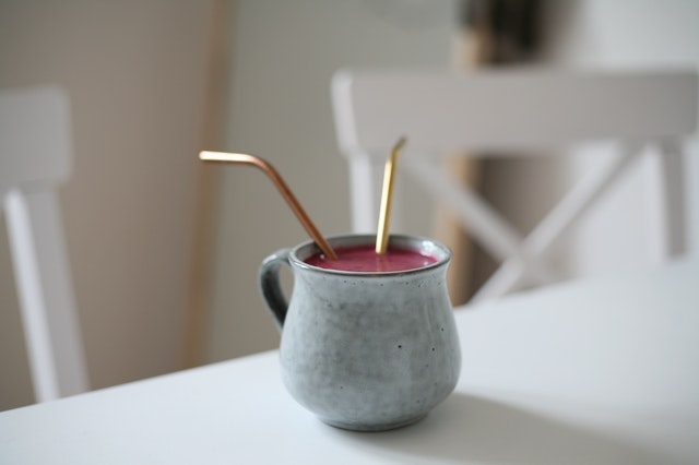 Caneca cinza com líquido e canudos dentro.