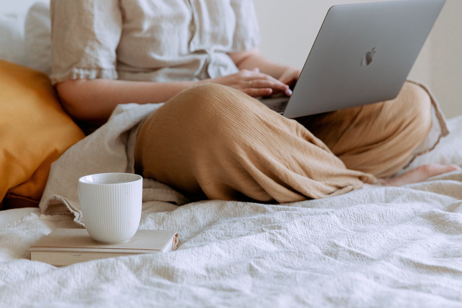 Mulher usando notebook sentada na cama