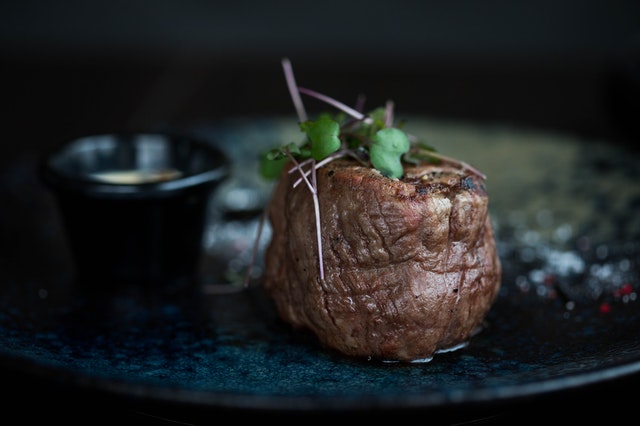 Pedaço de carne num prato preto.