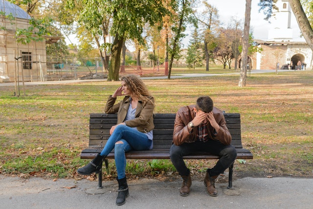 Homem e mulher brancos sentados em banco.