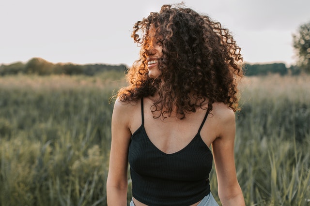 Mulher negra com expressão sorridente e cabelo no rosto.