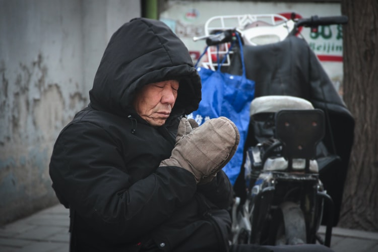 Um senhor japonês rezando em meio a rua