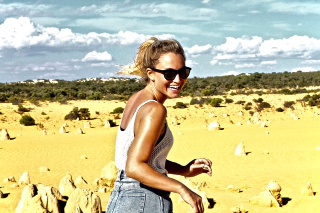 Mulher branca olhando para trás num deserto.