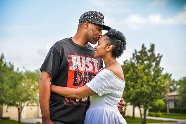 Homem negro beijando cabeça de mulher negra.