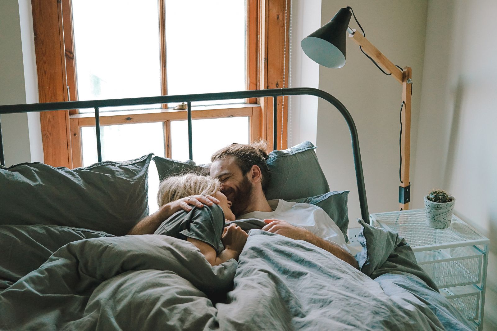 Homem e mulher deitados na cama sorrindo