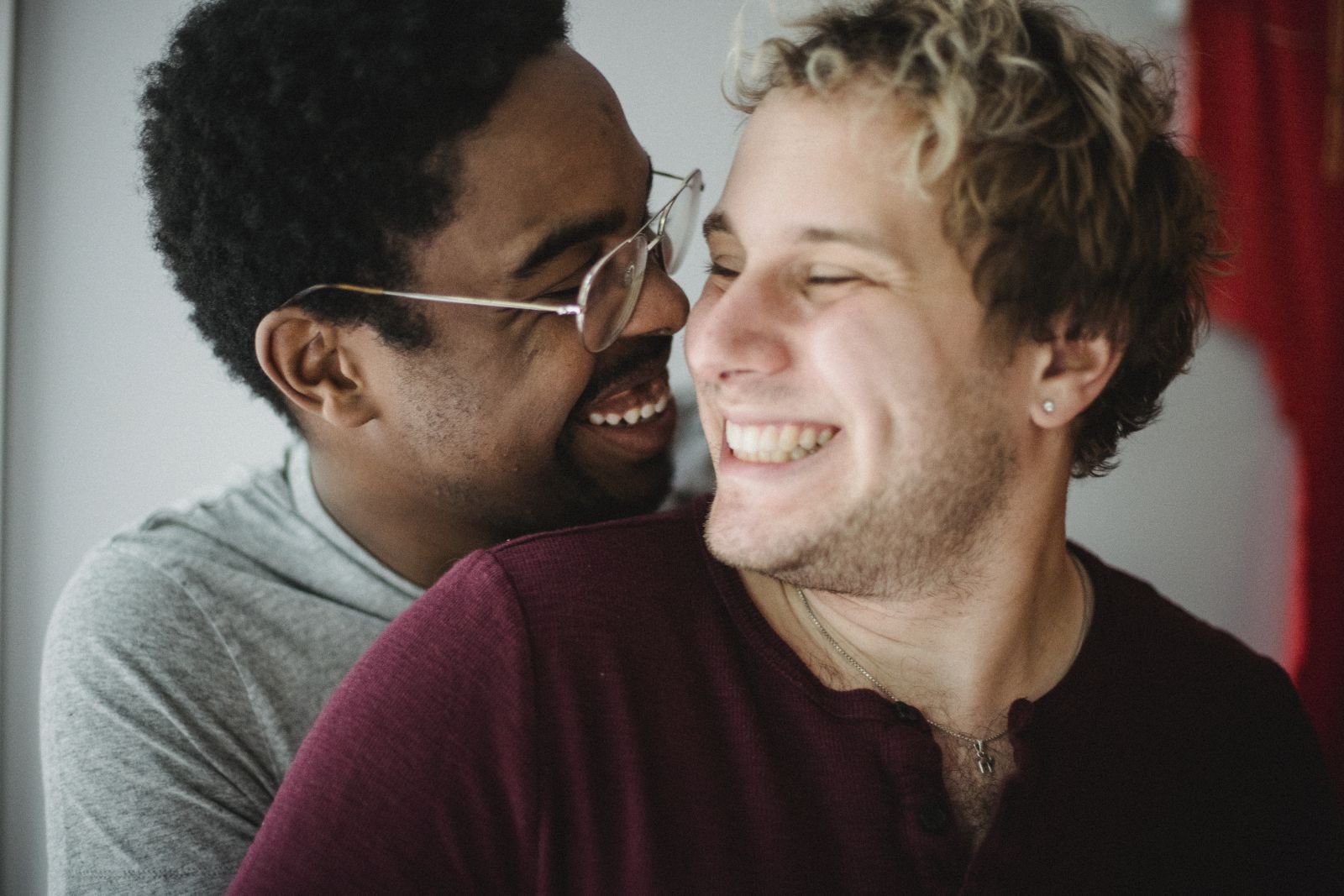 Dois homens abraçados, sorrindo um para o outro.