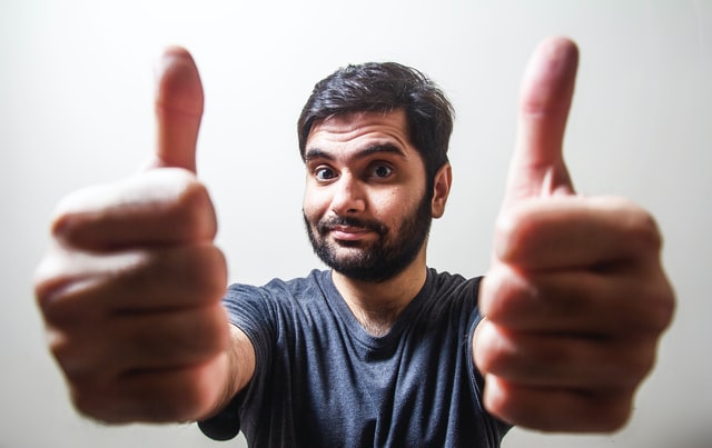 Homem branco com os polegares levantados.