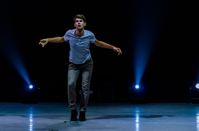 Homem branco atuando num palco.