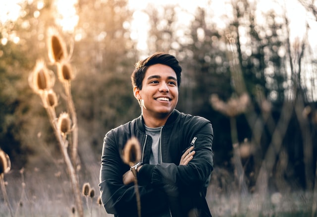 Homem branco sorrindo com os braços cruzados.