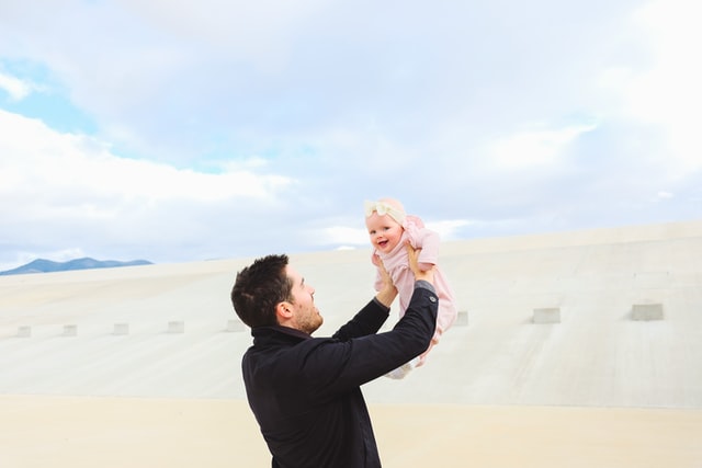 Pai segurando sua bebê no ar, acima de sua cabeça