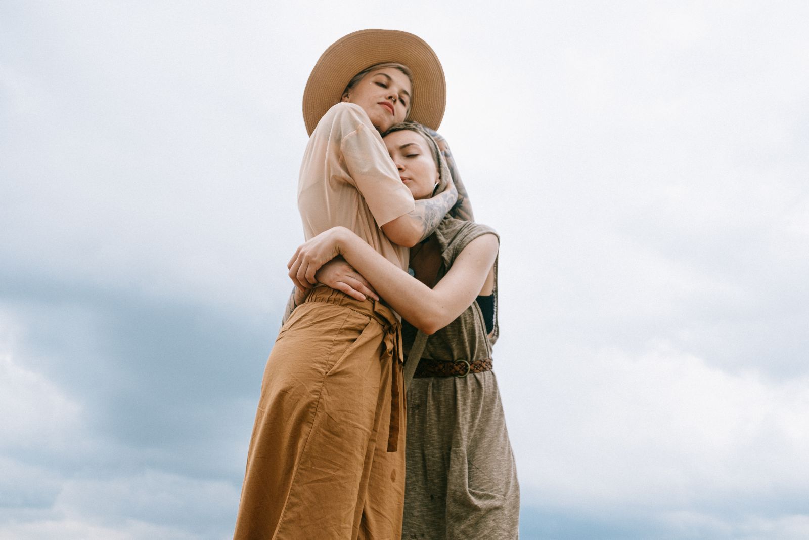Duas mulheres abraçadas em frente ao céu ensolarado.