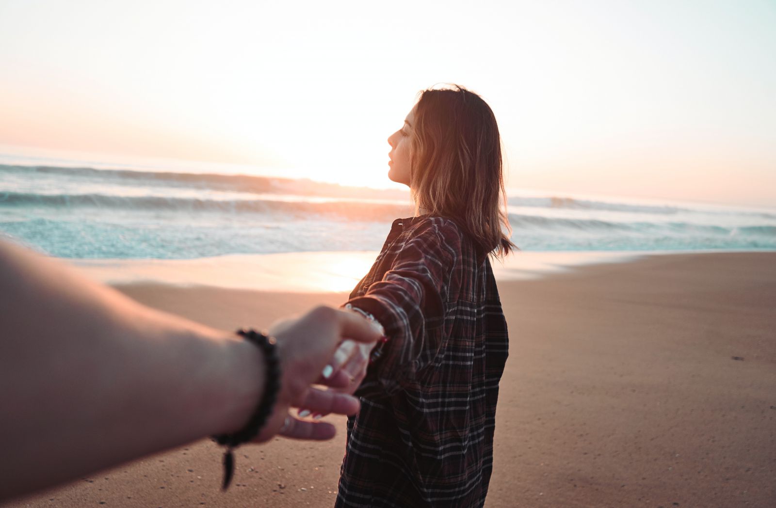 Mulher segurando mão de homem em uma praia